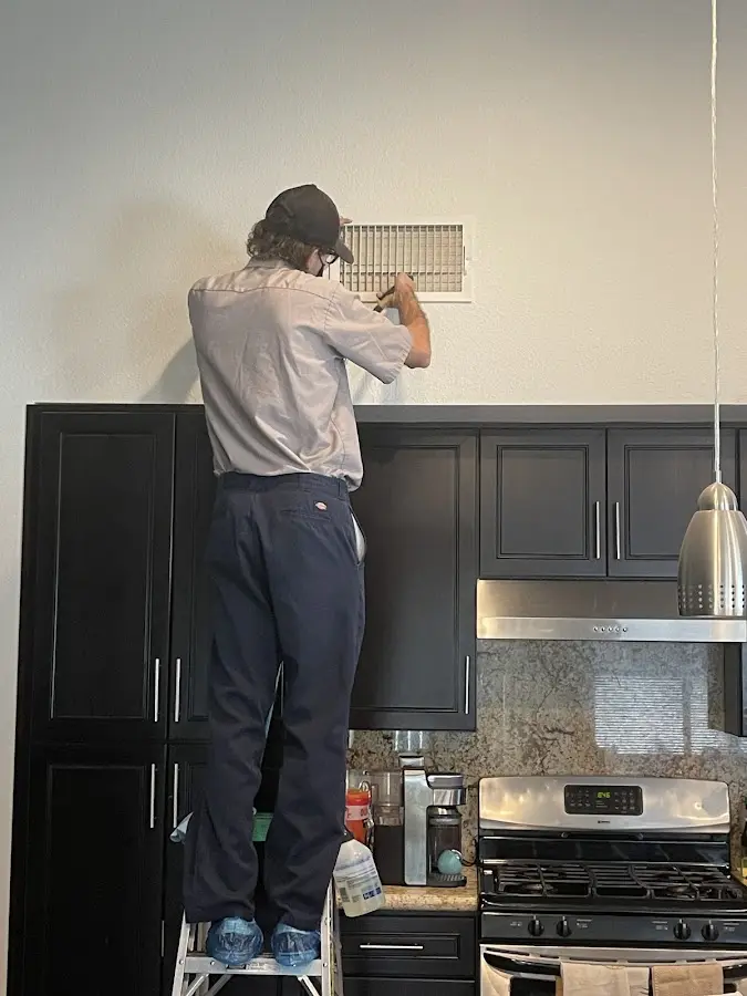 Technician inspecting an air vent during HVAC service in Kennewick